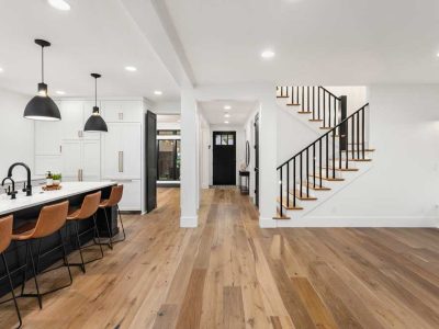 Kitchen And Living Room Interior In New Farmhouse Style Luxury Home With Open Concept Floor Plan Features Large Island With Farmhouse Sink Hardwood Floors And Black Accents