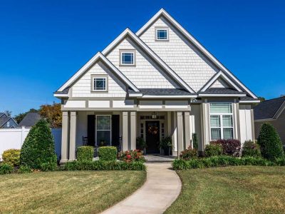 The Front View Of A Cottage Craftsman Style White House With A Triple Pitched Roof With A Sidewalk Landscaping And Curb Appeal